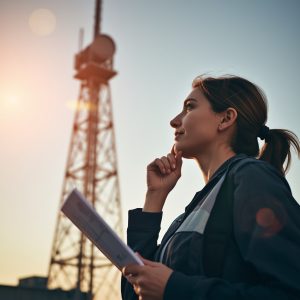 lucid-origin_A_woman_engineer_looking_thoughtfully_at_a_tall_communication_tower_sketch_in_ha-0